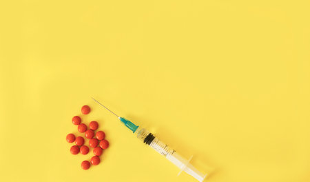 Syringes and pills on a yellow background. Place to write. Medicine conceptの写真素材