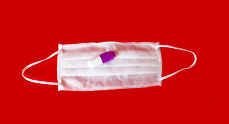 A new disease caused by the virus. On a red background lies a mask with a pill from the virus