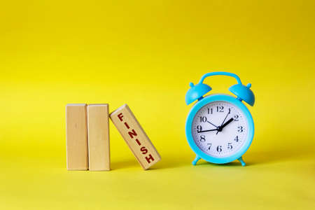 Blocks with the text FINISH on a yellow background, next to a blue alarm clockの写真素材
