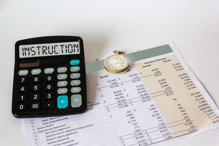 On the display of the calculator the word INSTRUCTION. On a white background financial document and...