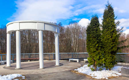 White columns in the form of a rotunda on the shore of a reservoir in early spring in sunny weatherの写真素材