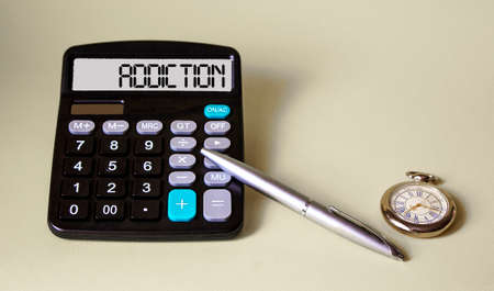 The word ADDICTION is written on the calculator's display, next to a pen and a clock. Health and drug addiction concept,の写真素材