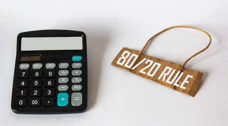 On a white background, a paper price tag with the text Rule 80 20, next to it is a calculator