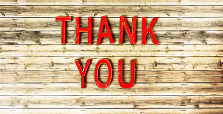 On a wooden background, red letters with the word THANK YOUの写真素材