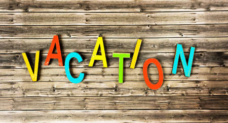 The word VACATION consists of multicolored letters on a wooden background.の写真素材