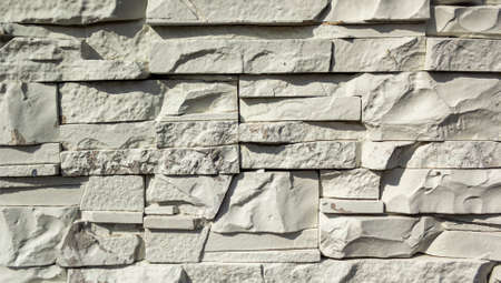 White stone wall. Rough exterior texture, uneven surface