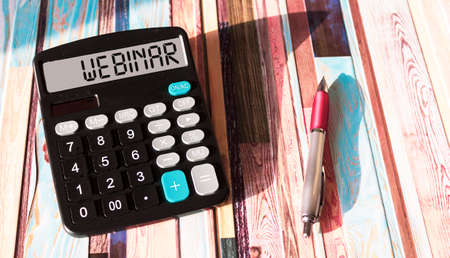The word WEBINAR is written on the calculator display. Business and finance concept. A pen on a colored background.の写真素材