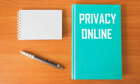 The diary says: ONLINE PRIVACY. There is a notepad and a pen on a wooden table.の写真素材