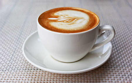 Hot art latte coffee in a cup on a white table
