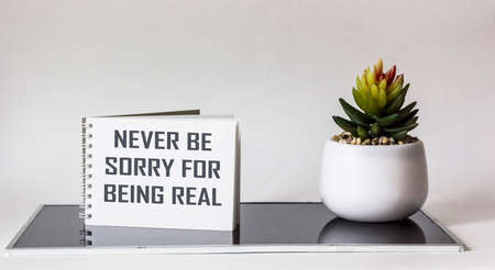 Never regret being real. Inspirational phrase on notepad, next to a cactus flower on a white and black background. Personal development conceptの写真素材