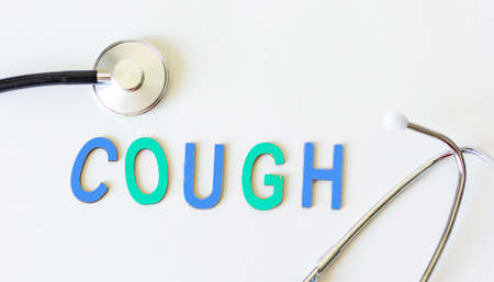 The word cough in wooden letters and with a stethoscope next to it on a white background. Conceptual...