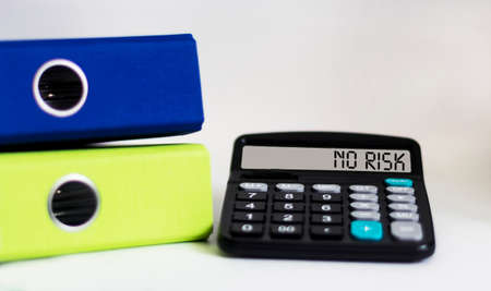 No Risk text on calculator display, white background with folders. Business concept.の写真素材