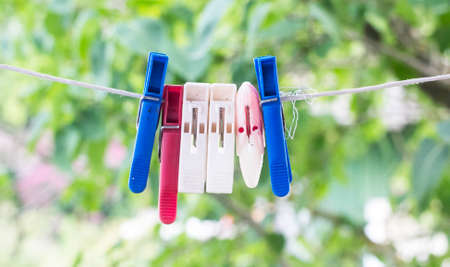 Colorful clothespins on a rope in the summer on the street. Multi-colored fabric clips on a white rope awaiting the next batch of clothes after washing.の写真素材