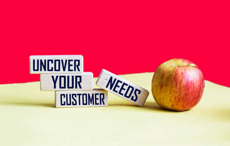reveal the needs of your customers. Text on wooden blocks and red and yellow background with appleの写真素材