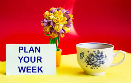 Plan your week highlighted in red on a sticky note posted against a yellow background as a reminderの写真素材