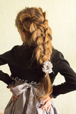 On the head of a little girl, in festive clothes, beautifully woven braids.