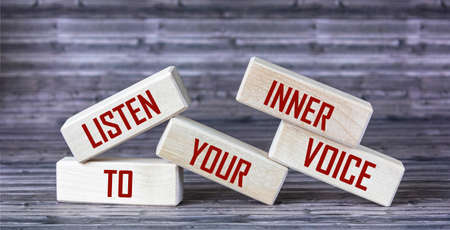Listen to your inner voice - the text is written on wooden blocks that lie on a wooden background.の写真素材
