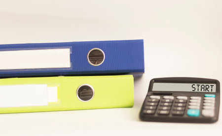 Calculator with text Start. Multi-colored folders with documents lie on a white background. Business and financial conceptの写真素材
