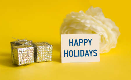 On a yellow background, a sign with the text HAPPY HOLIDAY, next to the boxes with giftsの写真素材