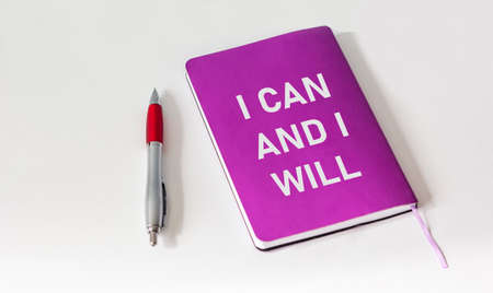 I can and I will be written on a colored notebook and a white background, next to a pen.の写真素材