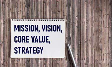 MISSION, VISION, CORE VALUE, STRATEGY A symbol of our core values. Conceptual words on notepad on wooden background. Business concept and our core values.の写真素材