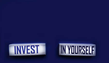 Invest in yourself. Motivational words in wooden alphabet letters isolated on blue background