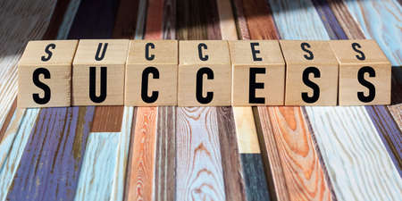 Word Success on wooden blocks and striped background.