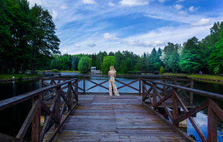 A girl stands on a bridge in Europe on a clear sunny day in summer. Back view of a girl.の写真素材