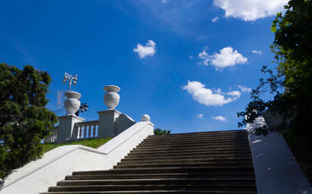 Stairway up with old fashioned white plaster vases in the park in summer.の写真素材