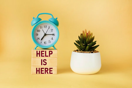 Help here and support symbol. Wooden blocks with the words Help here on a beautiful yellow...