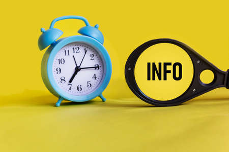 Info word on a magnifying glass on a yellow background with a clock. business concept.