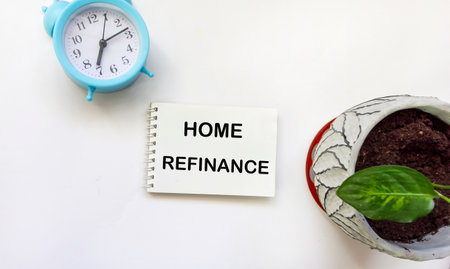 Notepad with text HOME REFINANCE with clock and flower on white backgroundの写真素材