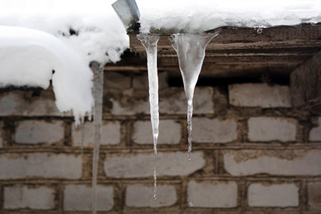 Icicles on the roof. winter concept. Snow on the roof. Brick white wall.