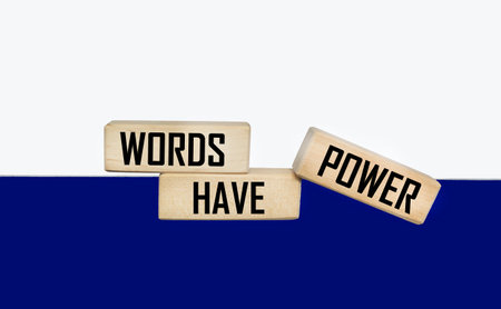 Words have power written on a wooden block and a white and blue photo.