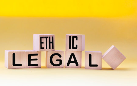 Ethical legal symbol. The words Ethical and Legal on wooden blocks and a beautiful yellow background. Business and ethical or legal concept. Copy space.の写真素材