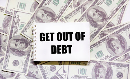 GET OUT OF DEBT text on paper with dollar bills