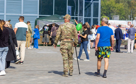 A soldier walks with a stick along a street where there are many peopleの写真素材