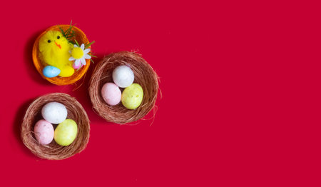 Lots of Easter eggs and a toy chicken in nests on a red background. Easter concept, close-up.