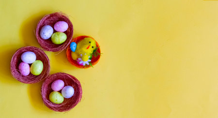 Easter eggs in three straw baskets and a basket with a chicken on a yellow background. A place to...