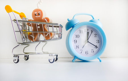A mini shopping basket on a white background next to an alarm clock. Sale, discount time, time saving concept.の写真素材