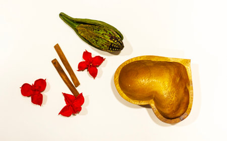 A lovely heartshaped bowl that is beautifully surrounded by vibrant red flowers and aromatic cinnamon sticks, creating a delightful sceneの写真素材