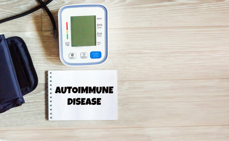 A text message about an autoimmune disease on a notebook with a blood pressure monitor on a wooden...