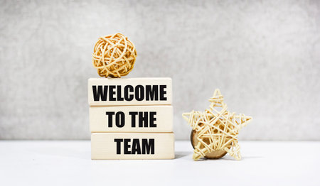 The symbol Welcome to our team on the wooden blocks. The background is grey.