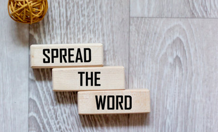 Wooden block with the text SPREAD THE WORD on a gray backgroundの写真素材