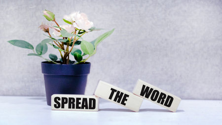 Wooden block with the text SPREAD THE WORD on a gray backgroundの写真素材