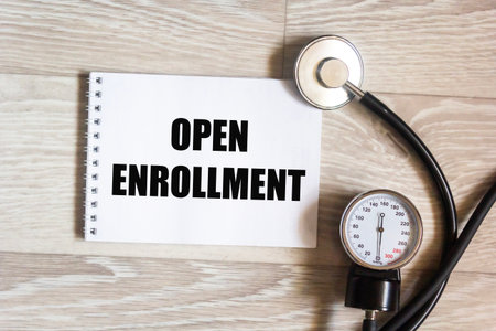 Stethoscope and notepad with text open enrollment Medical concept
