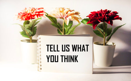 A businesslike and positive concept. There's a notebook on the table with the text written on it - TELL US WHAT YOU THINK.の写真素材