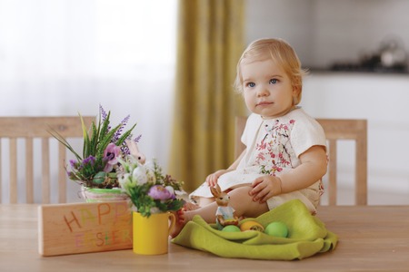 Happy child sitting at the table and holding easter eggの写真素材