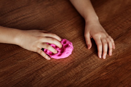 The child is holding a toy called mucus, the child is having fun and experimenting.の写真素材
