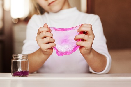 The child is holding a toy called mucus, the child is having fun and experimenting.の写真素材